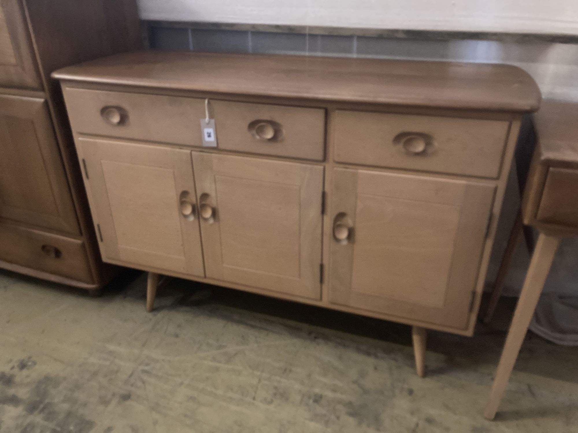 An Ercol elm sideboard (model no. 351), fitted one long drawer and one short drawer over three panelled doors, width 120cm depth 46cm h